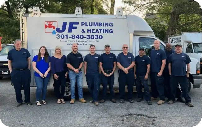 Group Of Ten People Standing In Front Of A Plumbing And Heating Company Truck, All Wearing Blue Uniforms Except One Person In Casual Attire.