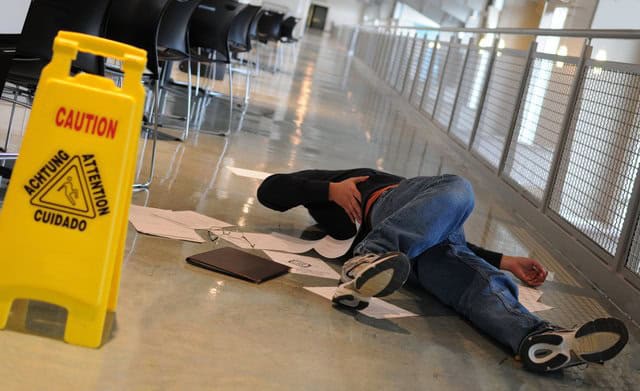 Hurt, lying on floor next to caution sign