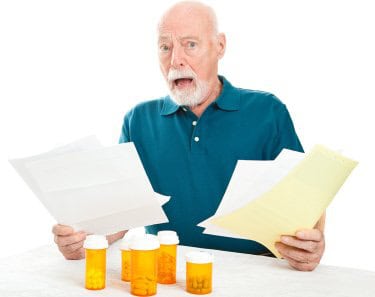 Man Stressed Holding Bills. Nex to Prescription bottles.