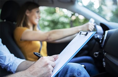 Photo d'une jeune conductrice conduisant en présence d'un formateur
