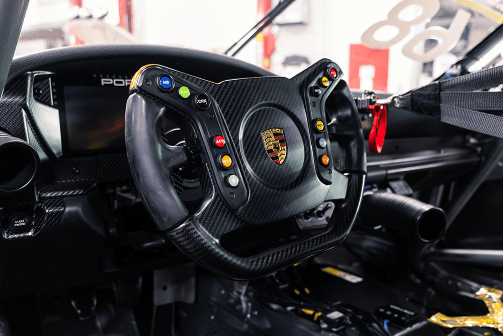 Close-up of Porsche 911 Cup Car racing steering wheel and dashboard.