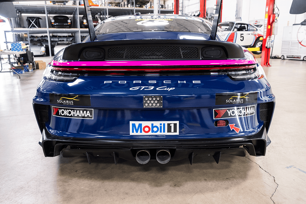 Rear view of a blue Porsche 911 Cup Car 992 in a garage.
