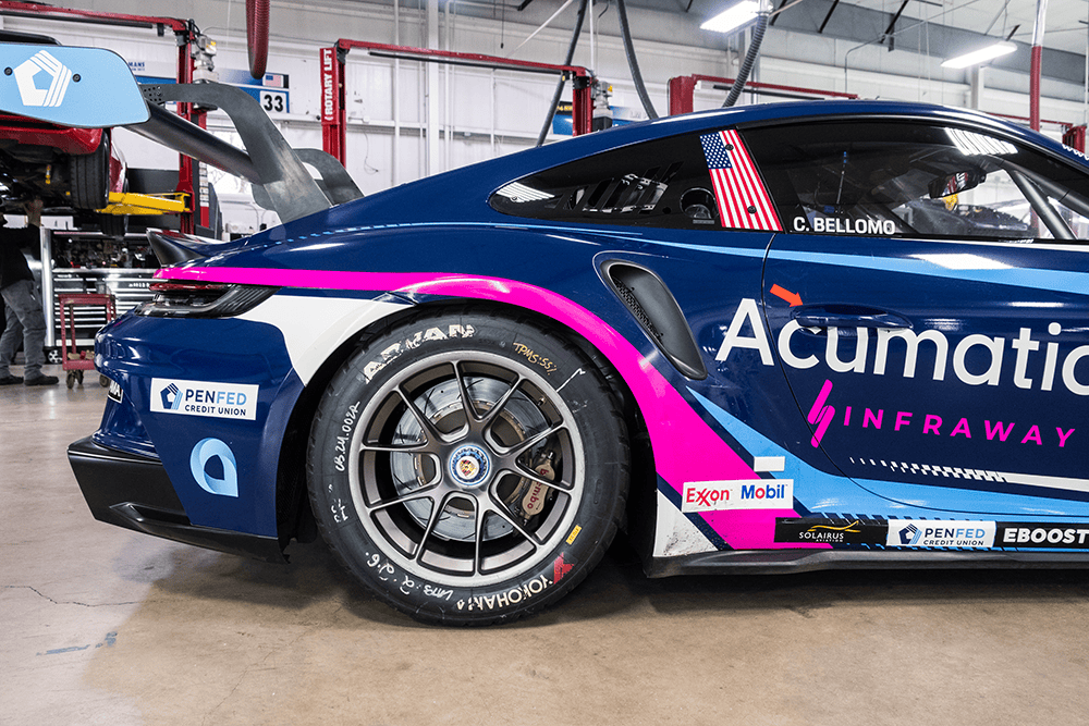 Blue Porsche 911 Cup Car 992 with pink accents in garage setting.