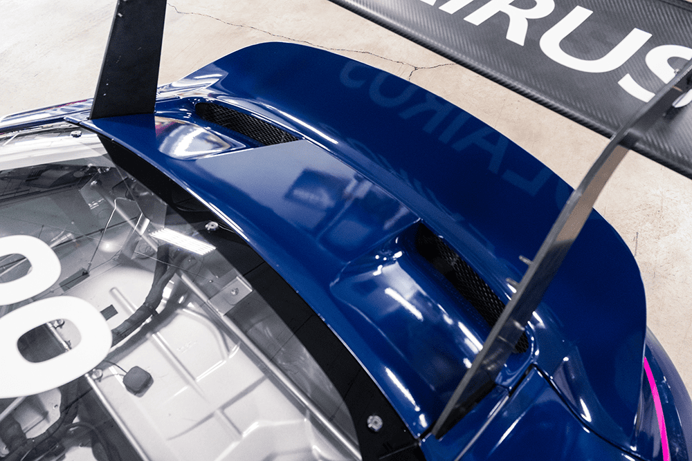 Close-up of blue Porsche 911 Cup Car 992 rear wing and aerodynamic features.