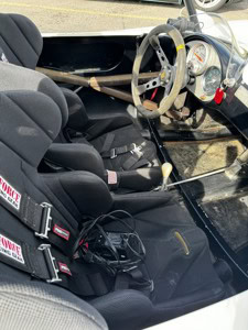 Close-up of vintage Porsche 550 Spyder interior with racing seats and steering wheel.
