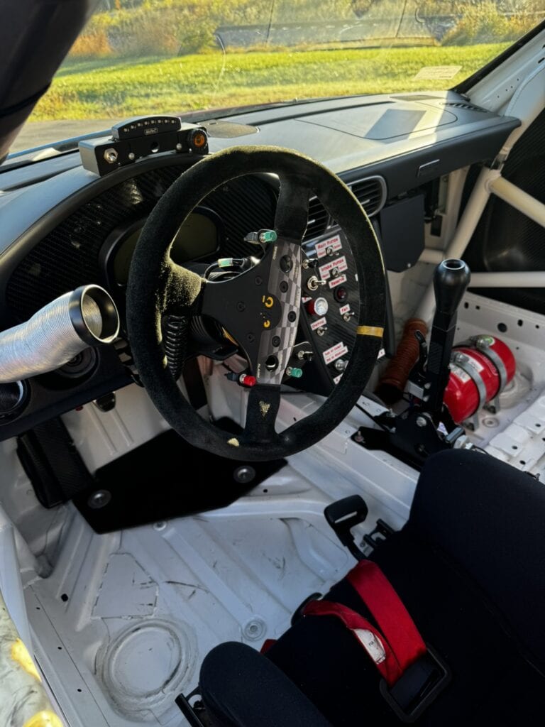 Racing car interior with steering wheel and dashboard details.
