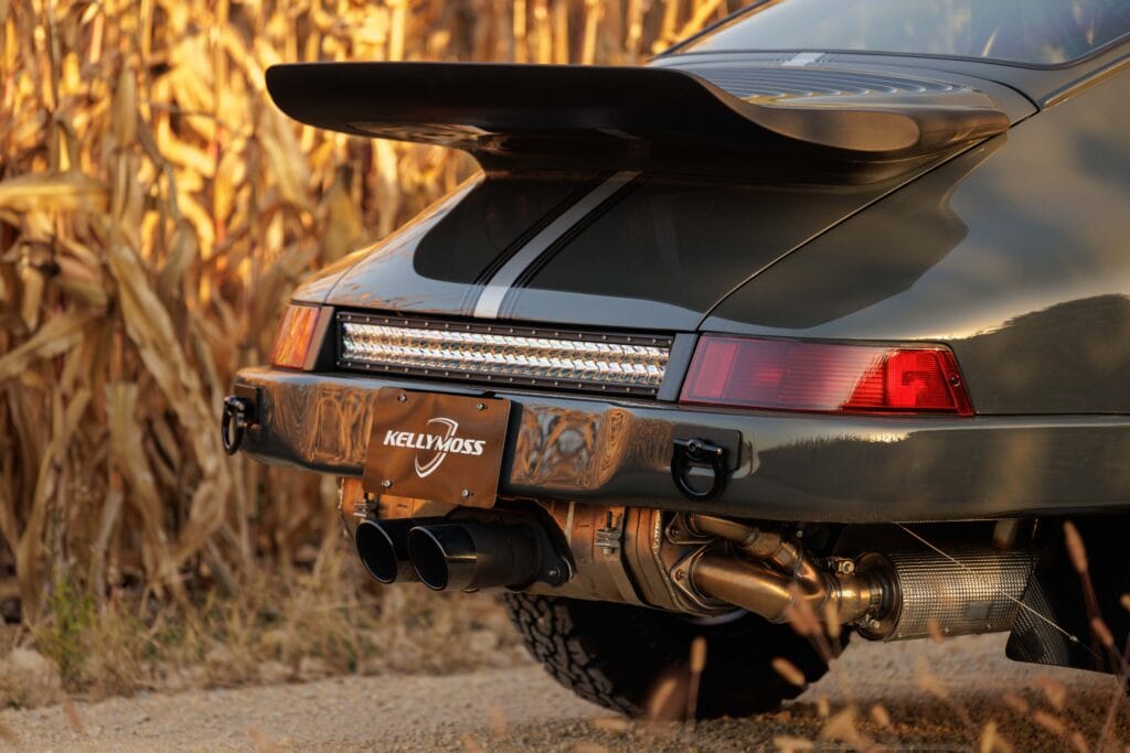 Close-up of a dark green Porsche 964 with a rear spoiler and custom exhaust.