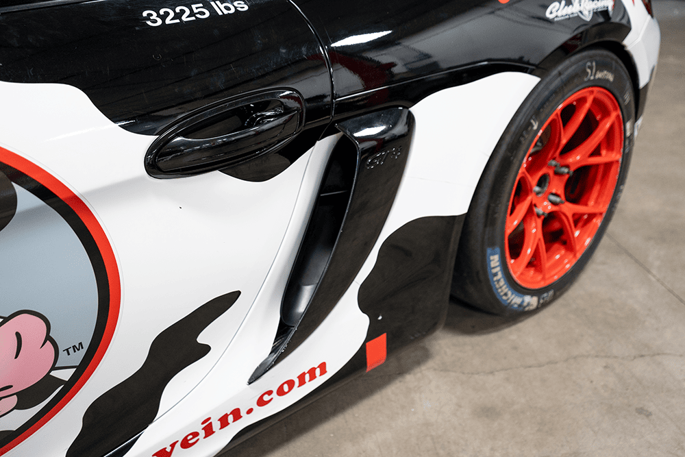 Close-up of Kellymoss Porsche 911 GT3 Cup 992 with red wheels and racing decals.