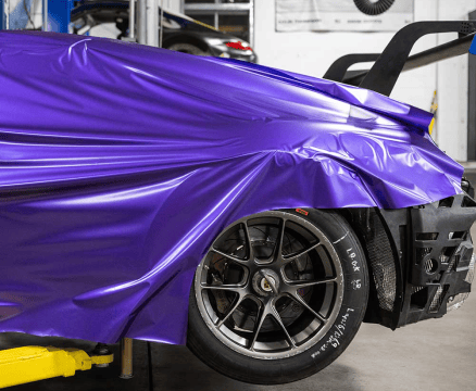 Purple car wrap being applied during the vehicle customization process.