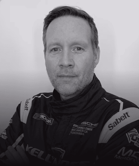Portrait of a race car driver in racing suit with sponsor logos.