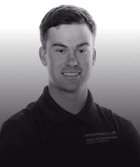 Portrait of a young man in a black Porsche polo shirt, smiling.