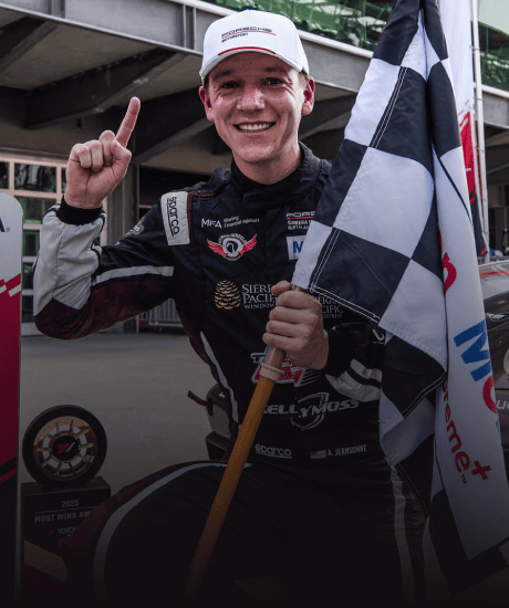 Race car driver celebrating with checkered flag at Porsche Carrera Cup North America.