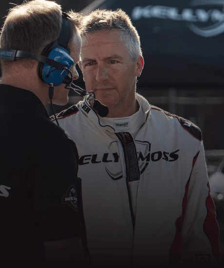 Two race car drivers in conversation at a Porsche event during the Porsche Club of America gathering.