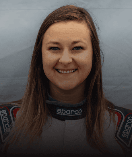 Portrait of a smiling woman race car driver in racing suit at Porsche Club event.