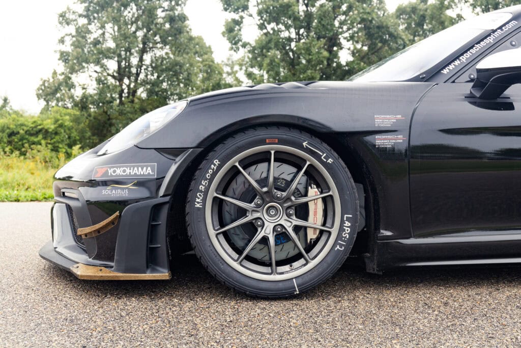 Close-up of black 2025 GT4 Clubsport RS race car wheel and front bumper.