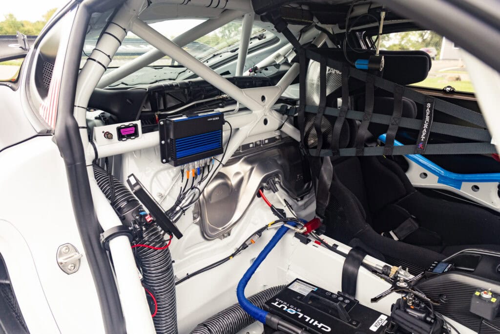 Race car interior with roll cage, racing seat, and electronic systems.