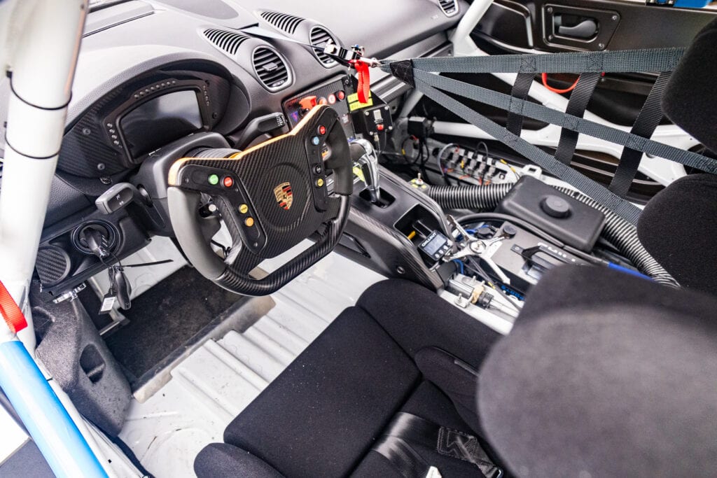 Race car interior with racing steering wheel and safety harnesses.