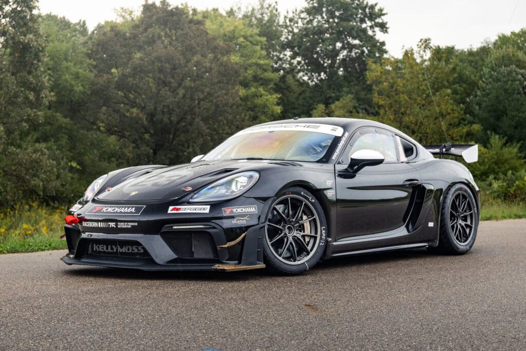 Black 2025 GT4 Clubsport RS race car on road with trees in background.