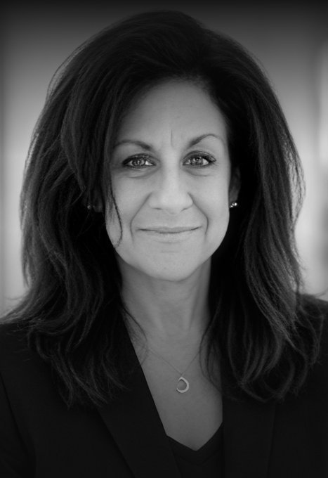 Professional portrait of a woman with dark hair and confident expression.