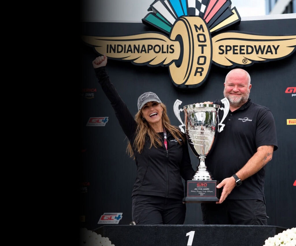 Kellymoss team celebrating victory with trophy at Indianapolis Speedway.