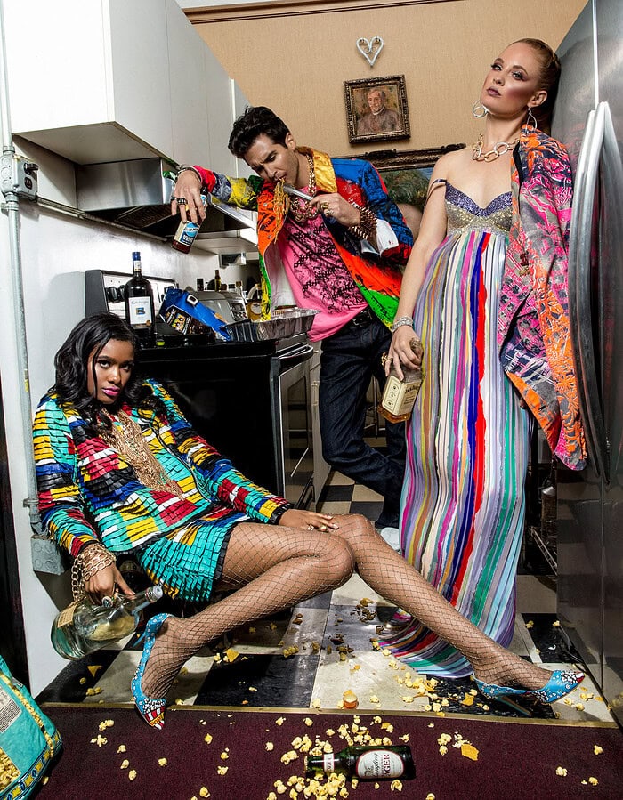 Fashion photo with three models in colorful outfits in a kitchen setting.