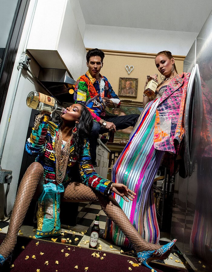 Fashion models in colorful, eclectic outfits in a modern kitchen setting.