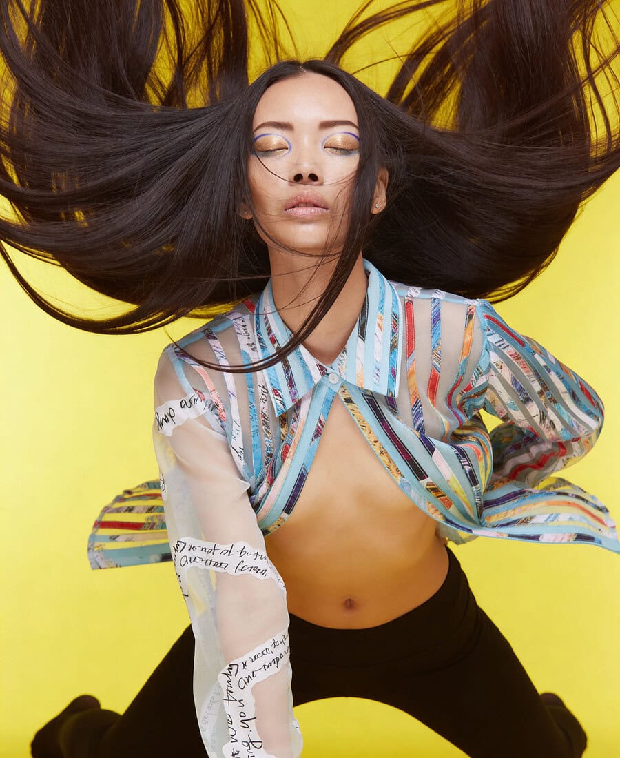 Fashion portrait of a woman with flowing hair against yellow background. photographer NYC