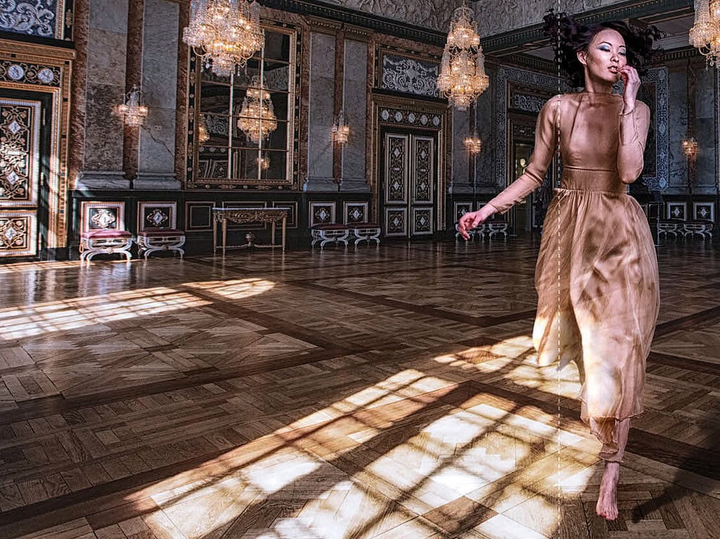 Elegant woman in a gold dress dancing in a luxurious ballroom with chandeliers. photographer NYC