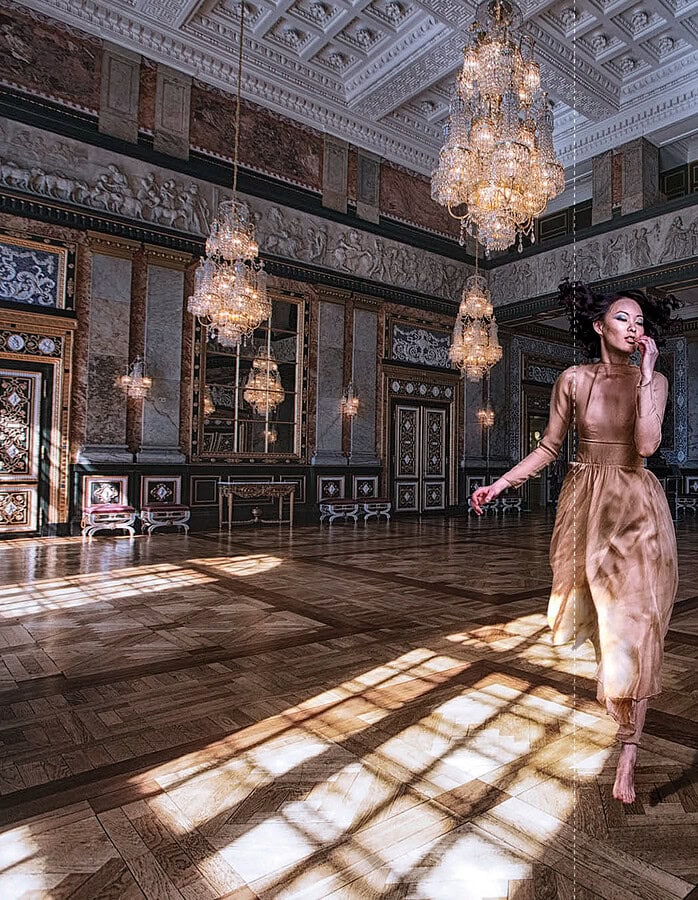 Elegant woman dancing in a luxurious, ornate ballroom with chandeliers. photographer NYC