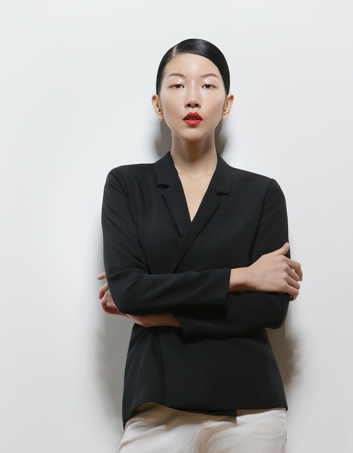 Elegant Asian woman in black blazer and beige pants against white background. photographer NYC
