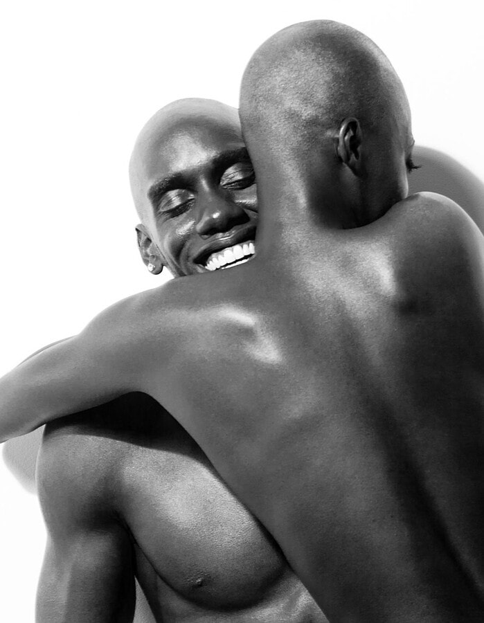 Male model smiling while embracing a female model in a black-and-white portrait.