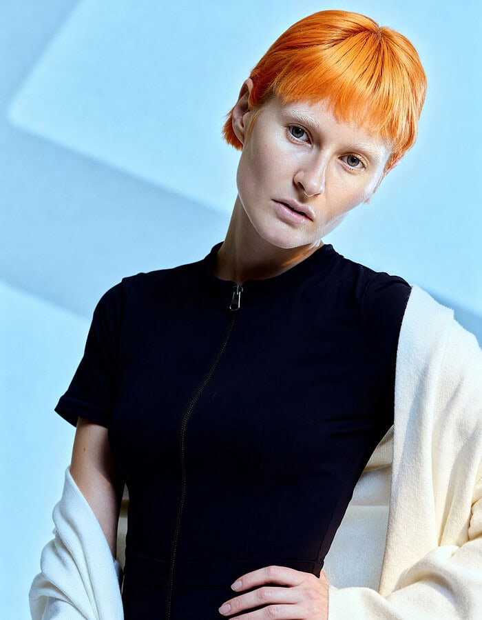 Portrait of a woman with short red hair wearing a black top and cream jacket. photographer NYC