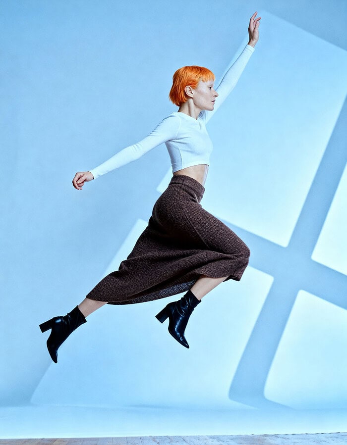 Fashion model jumping in studio with blue background and geometric shadows. photographer NYC
