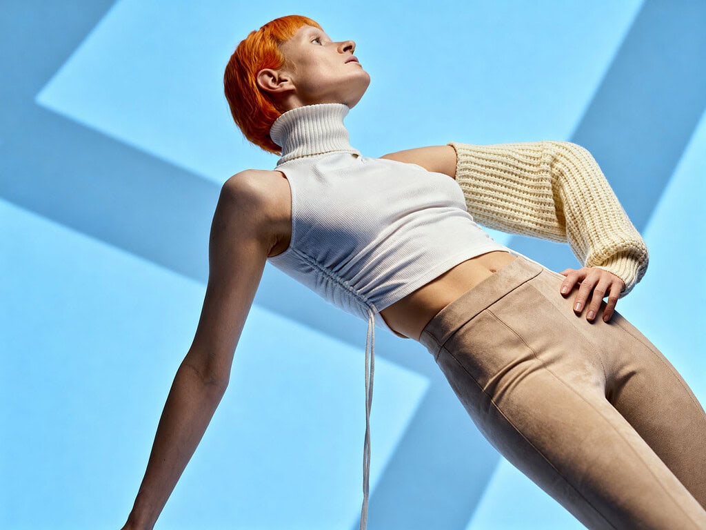 Fashion model with orange hair posing against blue geometric background. photographer NYC