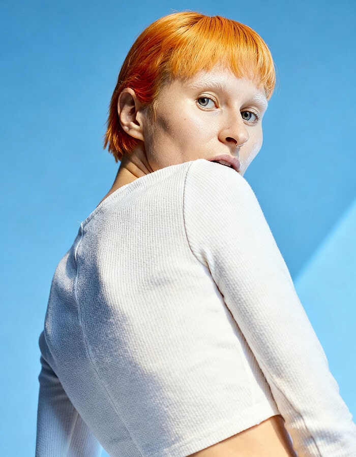 Portrait of a woman with short red hair against a blue background. photographer NYC