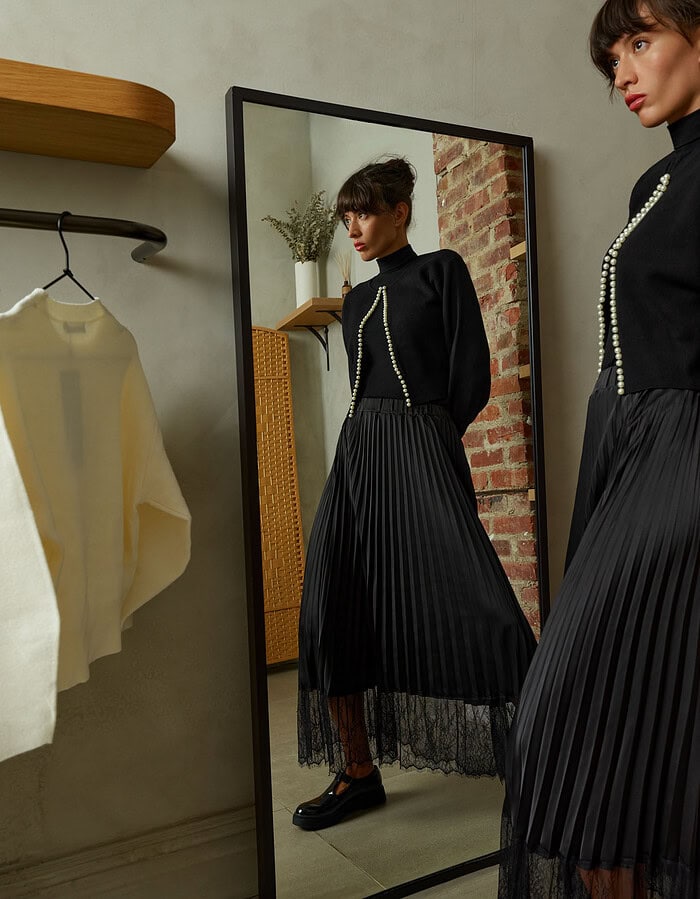 Fashion model in black pleated skirt and sweater reflected in mirror. photographer NYC
