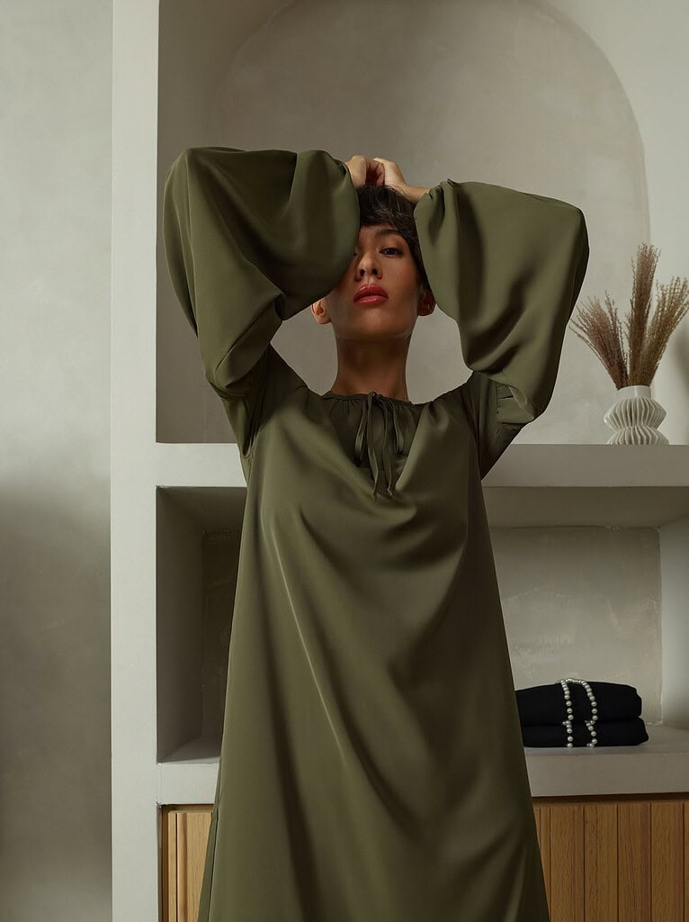Fashion portrait of a woman in an olive green dress with large sleeves. photographer NYC