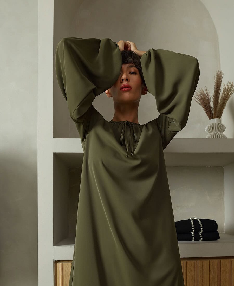 Fashion portrait of a woman in an olive green dress with large sleeves. photographer NYC