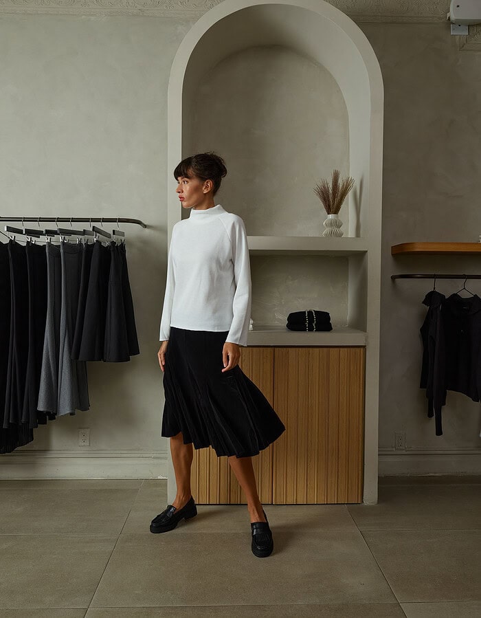 Fashion model in minimalist boutique wearing white top and black pleated skirt. photographer NYC