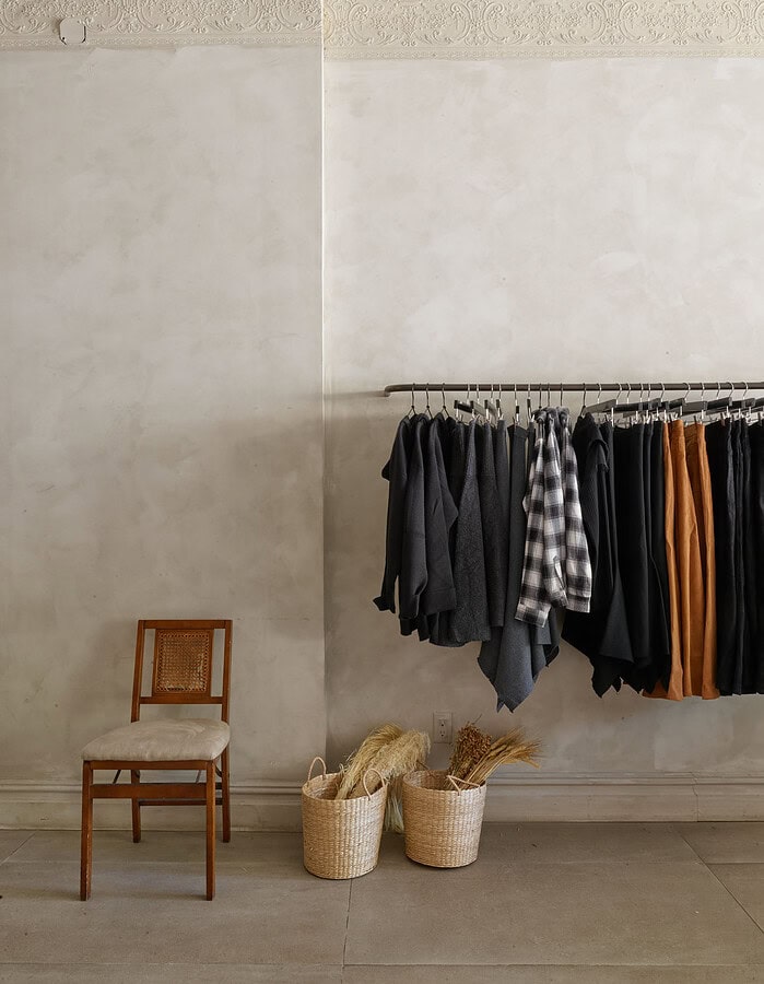 Clothing rack with dark and checkered garments in a minimalist boutique setting. photographer NYC