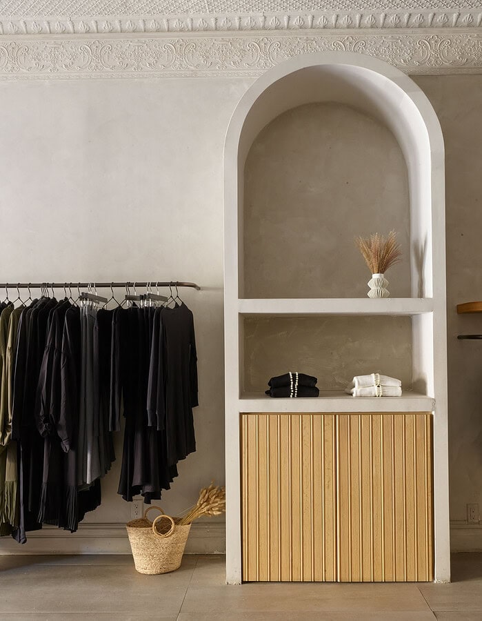 Minimalist clothing display with black garments and a wooden cabinet in a modern boutique. photographer NYC