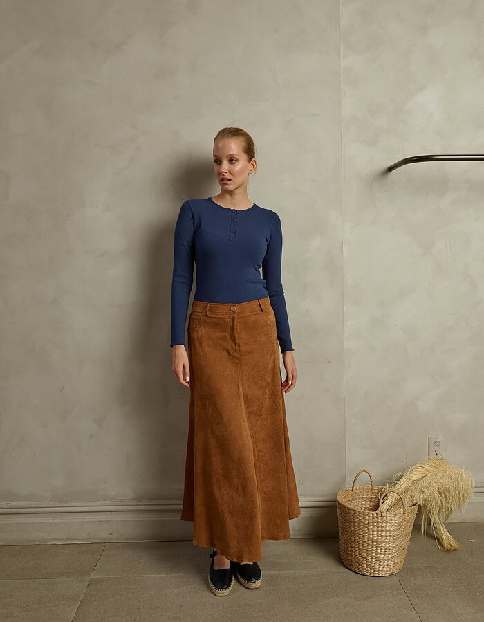 Fashion model in a blue top and brown skirt standing indoors. photographer NYC
