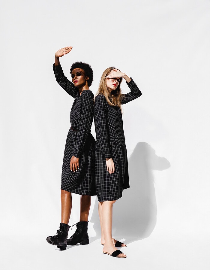 Two stylish women in black checkered dresses posing against a white background. photographer NYC