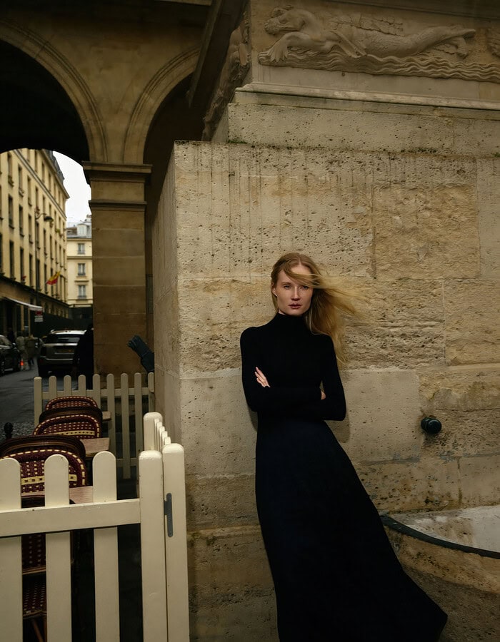 Elegant woman in black dress leaning against stone wall in Paris. photographer NYC