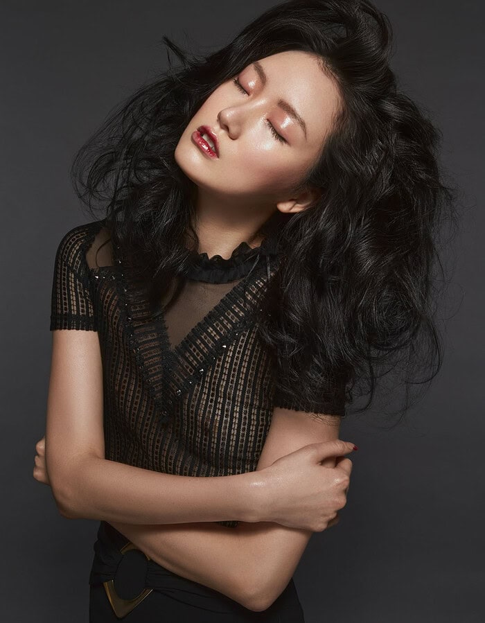 Portrait of a woman with black curly hair and closed eyes, wearing a black sheer top. photographer NYC