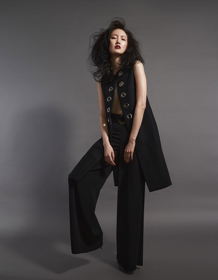 Fashion model in black outfit with wide-leg pants and sleeveless top on gray background. photographer NYC