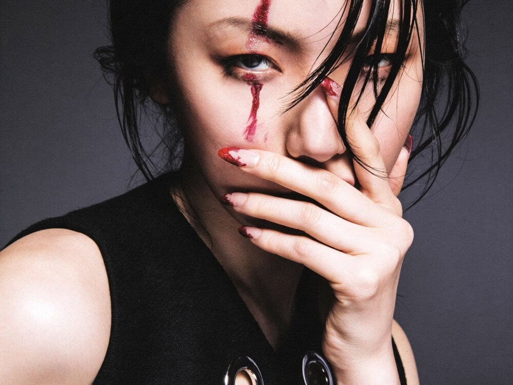 Close-up of a woman with makeup and tears on her face, covering her mouth with her hand. photographer NYC