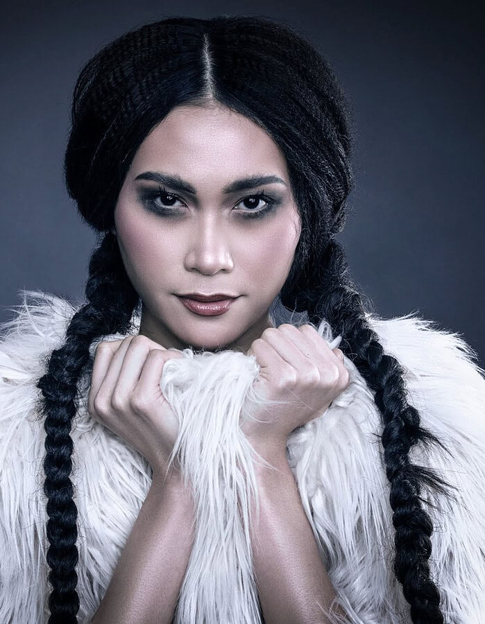 Close beauty portrait of a fashion model with long black braids framed by a white shaggy fur garment.