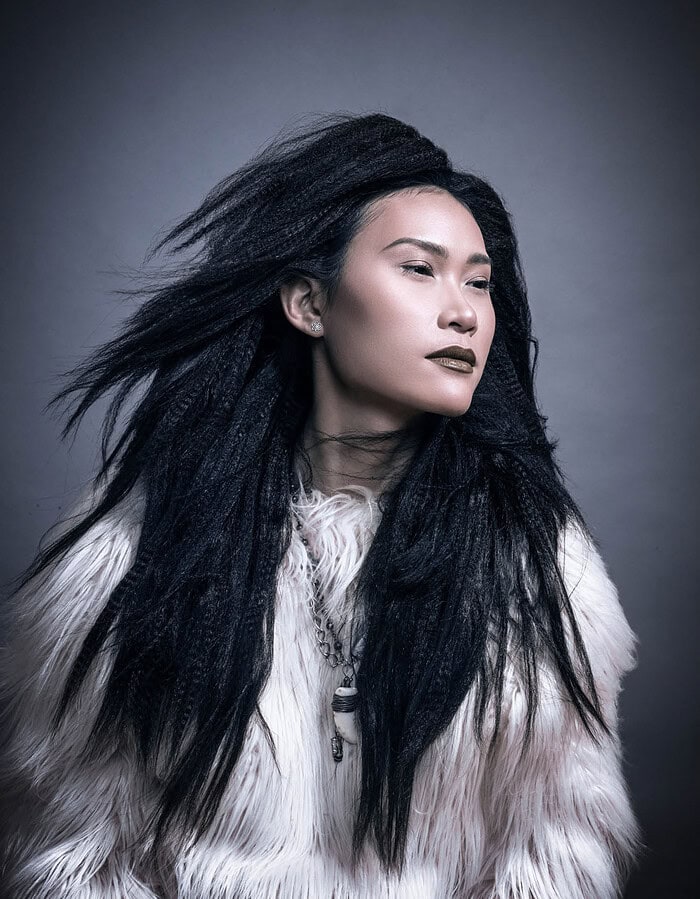 Beauty portrait of a fashion model with voluminous black textured hair wearing a white fur garment.