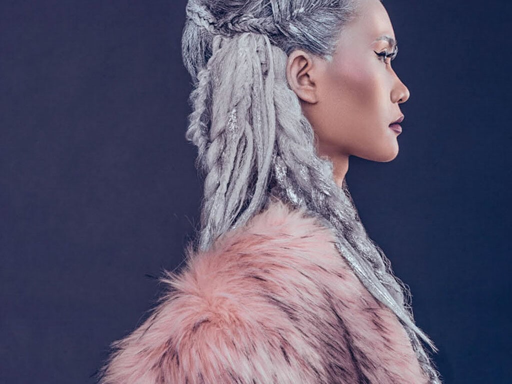 Close profile portrait of a fashion model with silver braided hair and a pink fur coat.